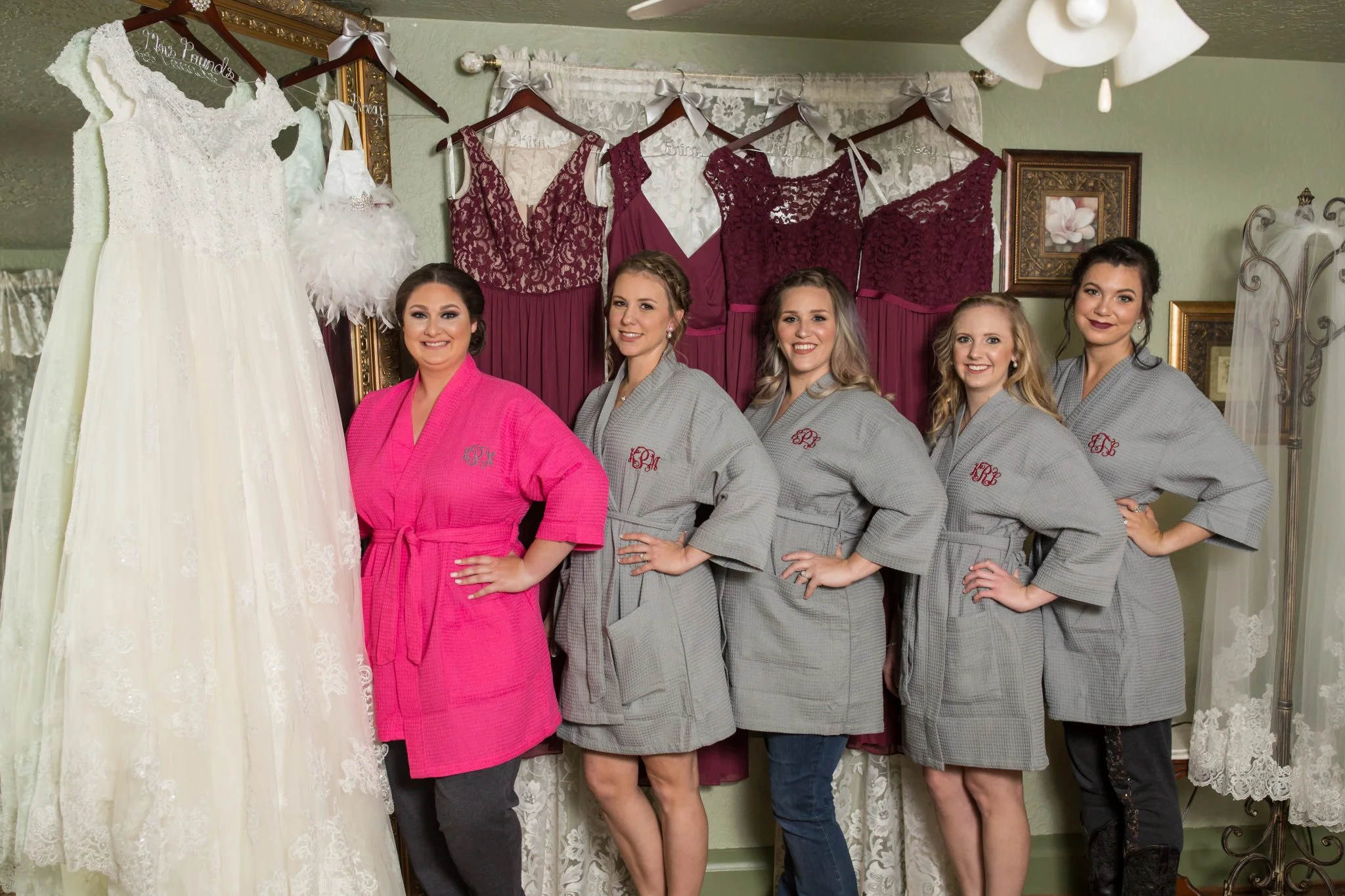 Wedding gown and burgundy bridesmaid dresses hung in the cottage